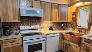 A kitchen with wooden cabinets, a built-in microwave, a stainless steel oven, a dishwasher, and a copper sink. - Freshly done, Quiet & very comfortable house in the heart of the White Mountains (Bartlett)