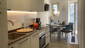 A modern kitchen with a built-in oven, a coffee machine, and a dining area with a table and chairs. - 2 vacation apartments for up to 6 people, perfect for a vacation with family or friends (Idro)