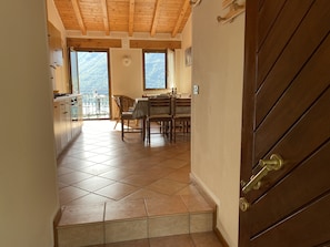 A kitchen with a dining area, wooden ceiling, and a view through the windows.