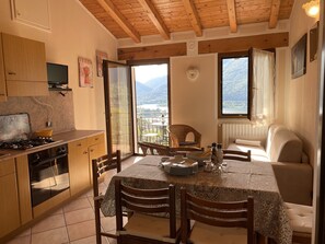 Une cuisine chaleureuse avec des meubles en bois, une table à manger pour quatre personnes et une vue sur les montagnes par la fenêtre.