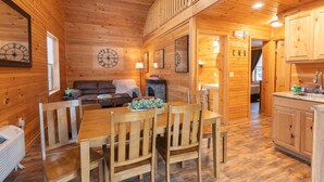 Ein Holzblockhaus-Interieur mit Esstisch, Stühlen, einer Couch und einer Küchenzeile.