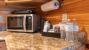 A kitchen with a microwave, a roll of paper towels, and bottled water on the counter.