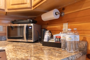 A kitchen with a microwave, a roll of paper towels, and bottled water on the counter.