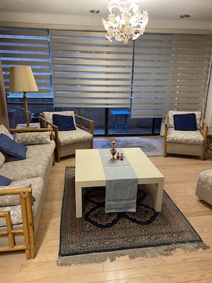 Ein Wohnzimmer mit einer Couch, zwei Sesseln, einem Couchtisch, einer Lampe und einer Chandelüster.