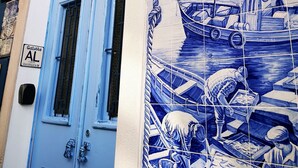 A building with a blue door and a tiled mural depicting maritime scenes. - Aluguer apartamento Gaivota (Portimão)