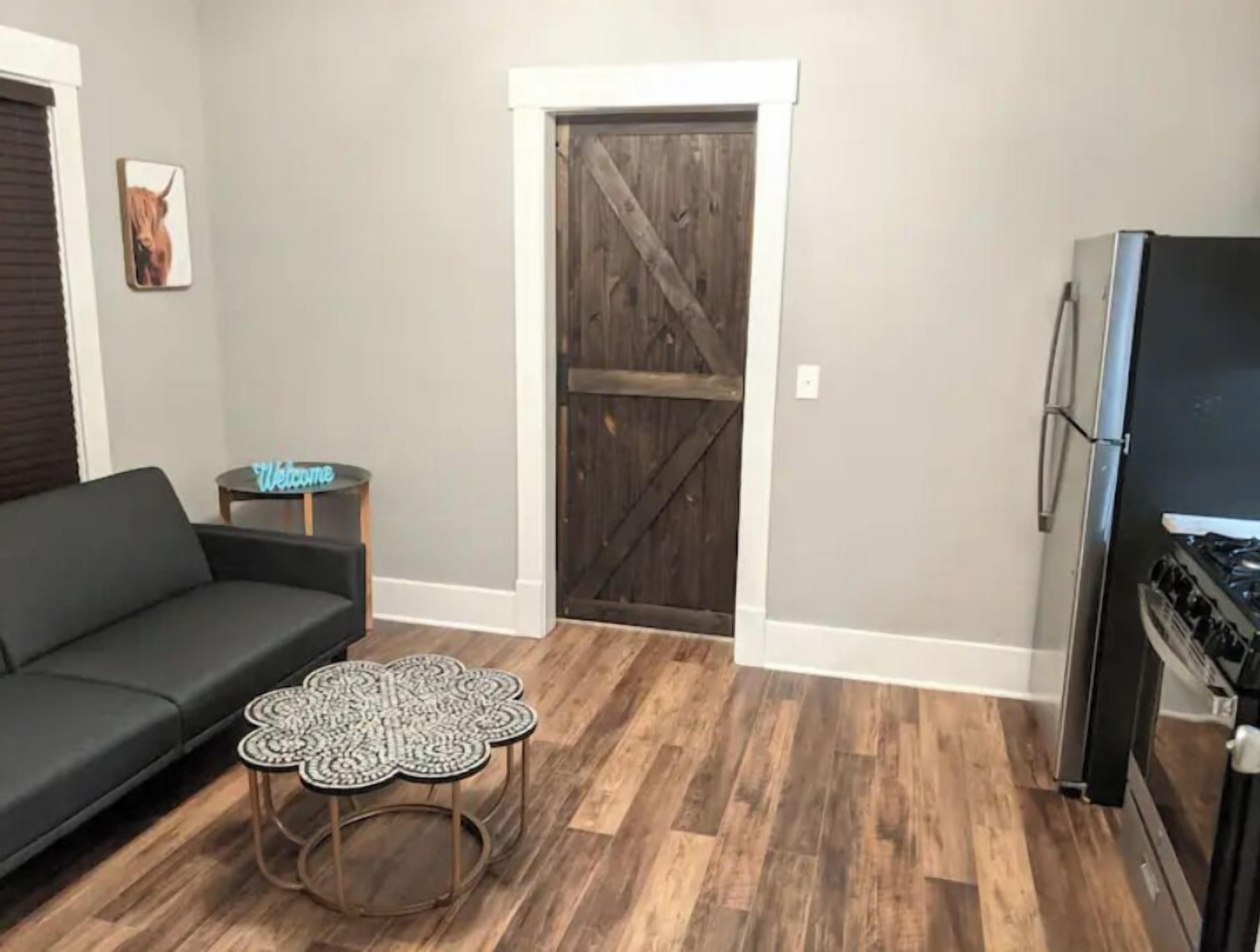 Ein Wohnzimmer mit Sofa, Couchtisch, Kühlschrank und Holztür.