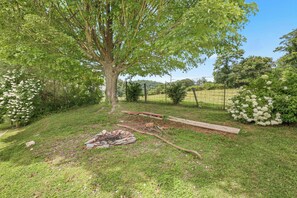 Relax in a serene outdoor space surrounded by a lawn, a large tree, and rolling hills.