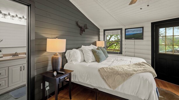 Un dormitorio con cama, lámpara de noche y una decoración de pájaro colgado.