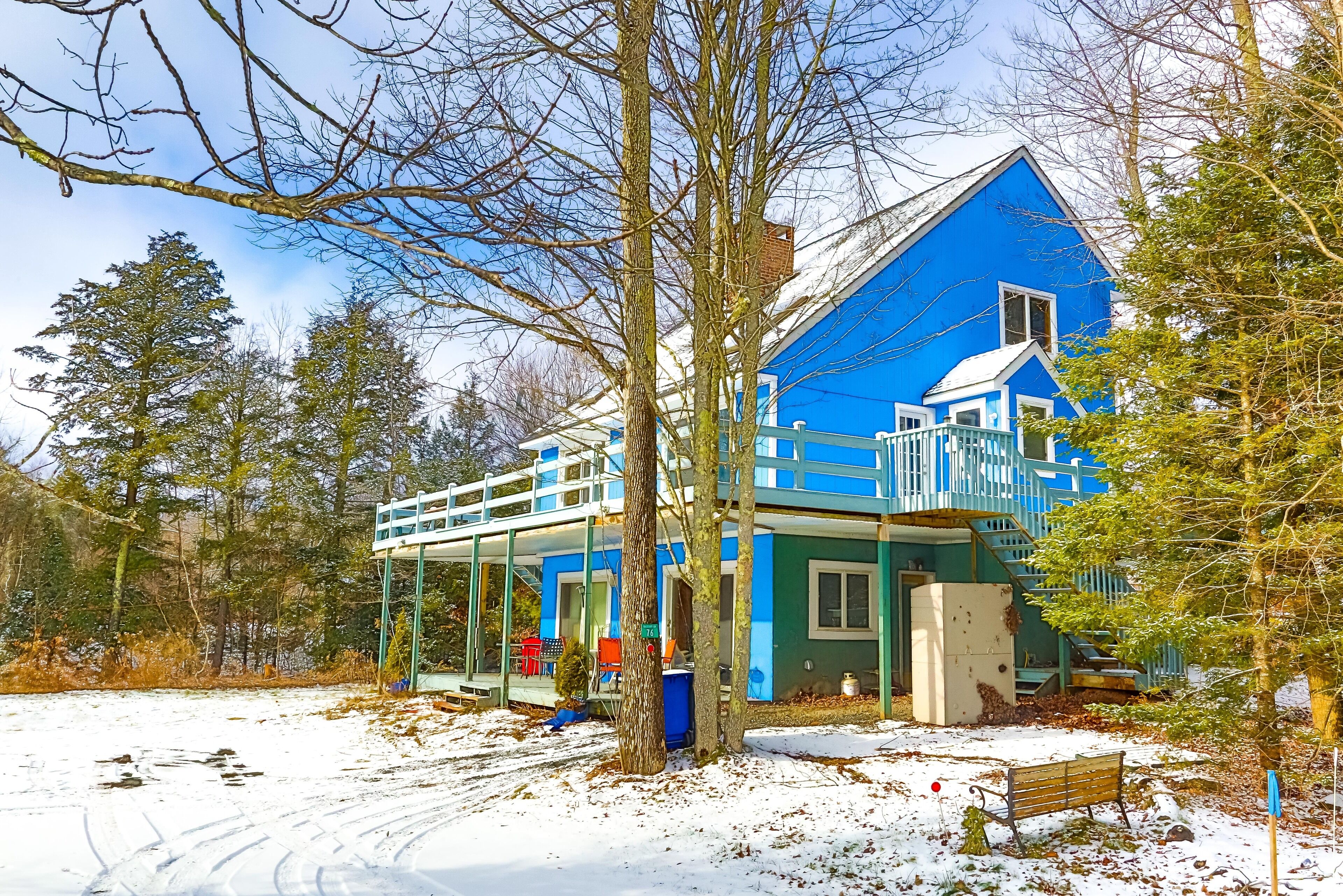 A blue house with a covered porch and a small deck.