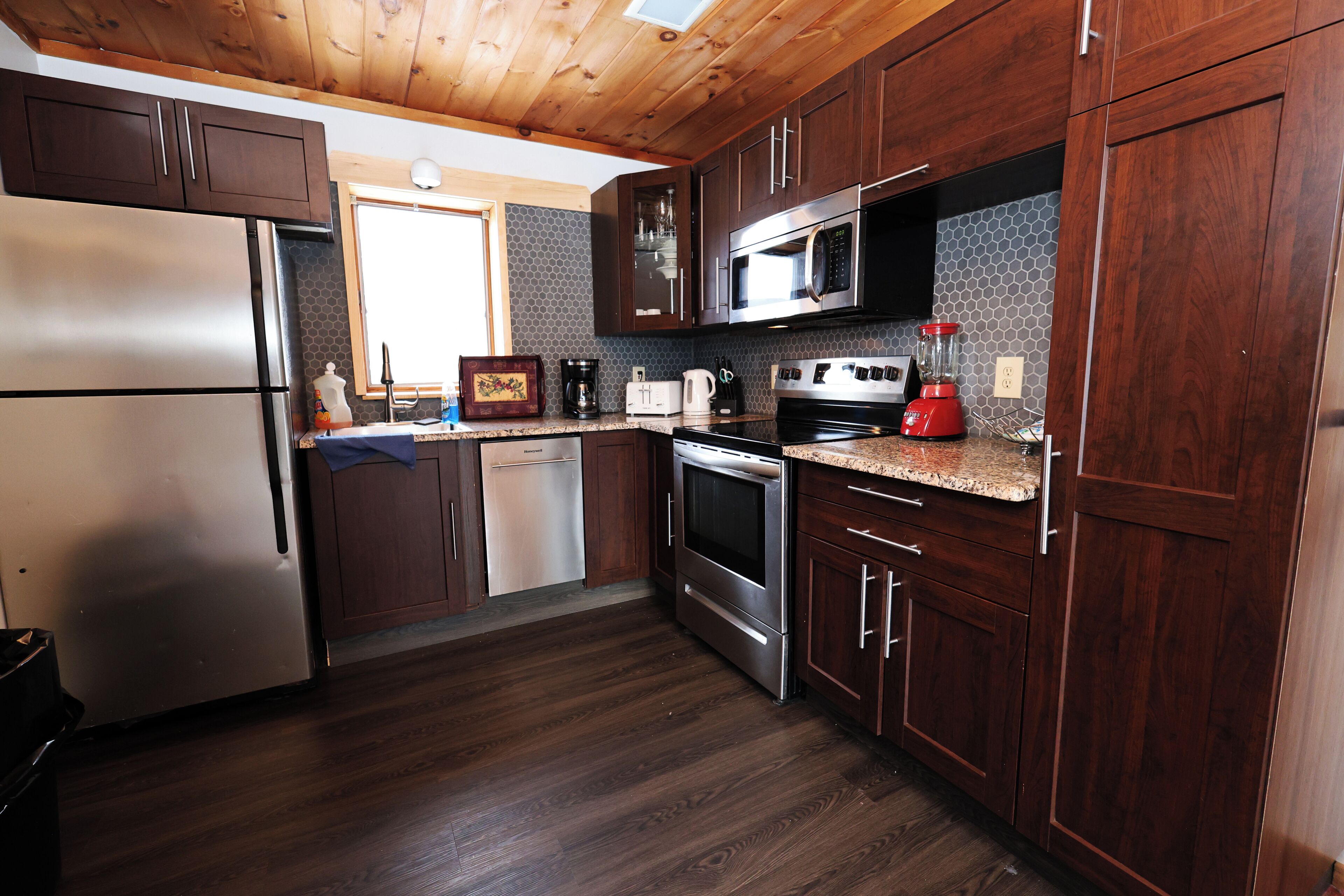 A kitchen with wooden cabinets, stainless steel appliances, and a tiled backsplash.