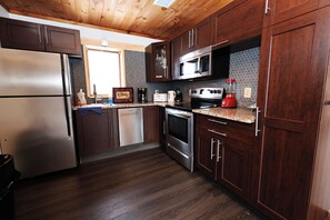A kitchen with wooden cabinets, stainless steel appliances, and a tiled backsplash. - Log Cabin Hot tub Private Pool 360 Mountain Views Hunter Mt (Tannersville)