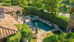 A private pool area with a stone-lined edge, surrounded by lush greenery and palm trees. - SPANISH TRADITIONAL - MOVIE COLONY EAST;  PS City ID #038084 (Palm Springs)