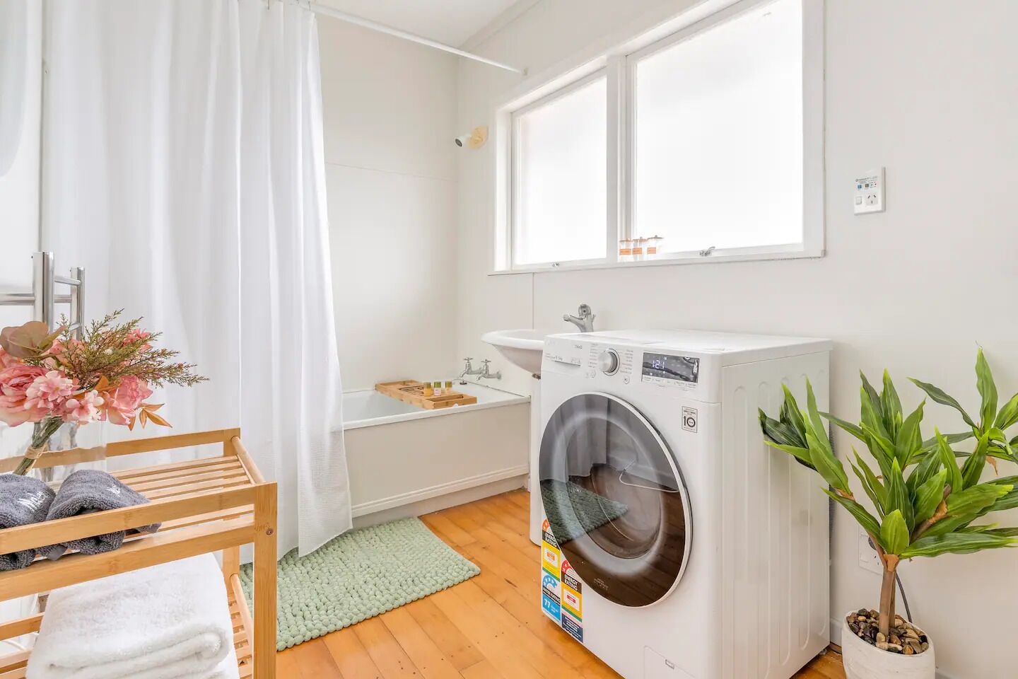 A laundry area with a washing machine, a sink, and a wooden bench with towels.