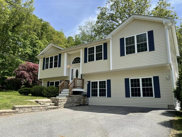 A two-story house with a front porch, a stone staircase, and a driveway.
