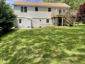 A two-story house with a front porch and a wooden staircase leading to a deck.