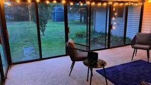 A covered patio with a sliding glass door, a laptop on a small table, and two chairs. - Salisbury (West Lafayette)