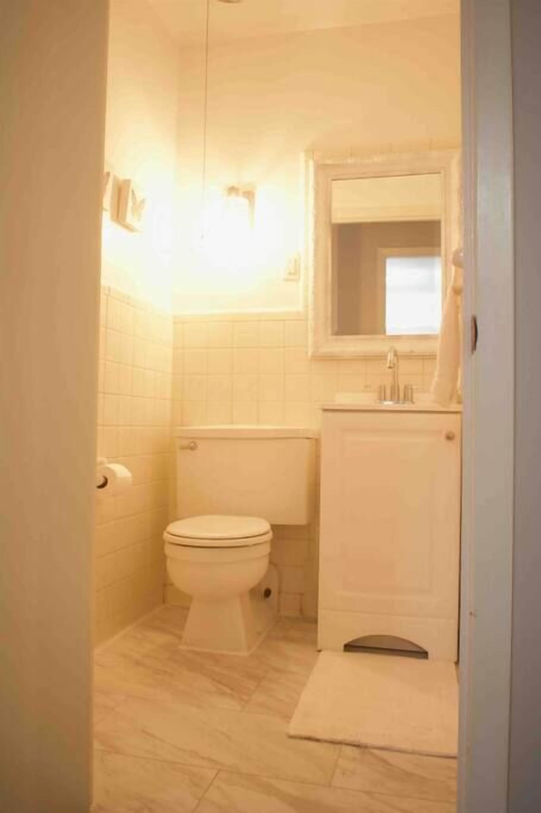 Un baño pequeño y funcional con inodoro, lavamanos y espejo.