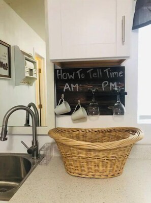 Kitchen area features a stainless steel sink, modern faucet, and a chalkboard with a clock.