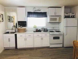 Kitchen with central island, microwave, and refrigerator, perfect for meal preparation and gathering.