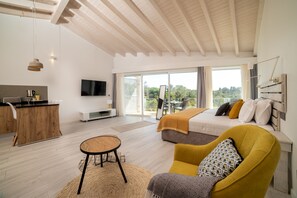 Un dormitorio moderno con cama, un sillón amarillo, una zona de comedor y un televisor.