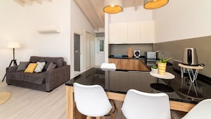 Una cocina moderna con una isla central, armarios blancos y un área de comedor con sillas blancas.