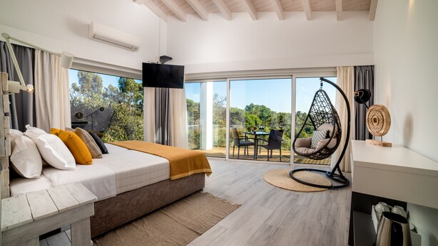 Un dormitorio moderno con una cama grande, una silla colgante y vistas al exterior.