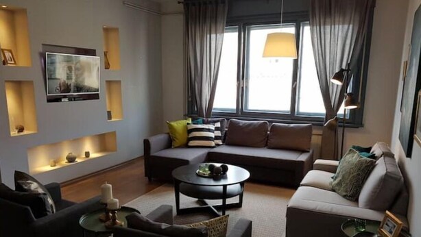 Una sala de estar moderna con un sofá, sillones, una mesa de centro y un televisor.