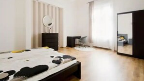 A modern bedroom with a bed, dresser, desk, chair, and a large mirror. - Downtown Rising Sun (104sqm 2bedr/2bath/living) (Budapest)