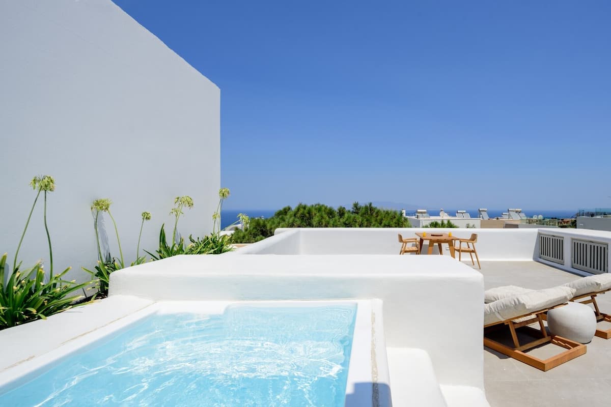 Een terras op het dak met een jacuzzi, lounge stoelen en uitzicht op zee.