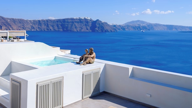 A rooftop pool area with a view of the sea and cliffs. - Oia Treasures Art Suites (Santorini)