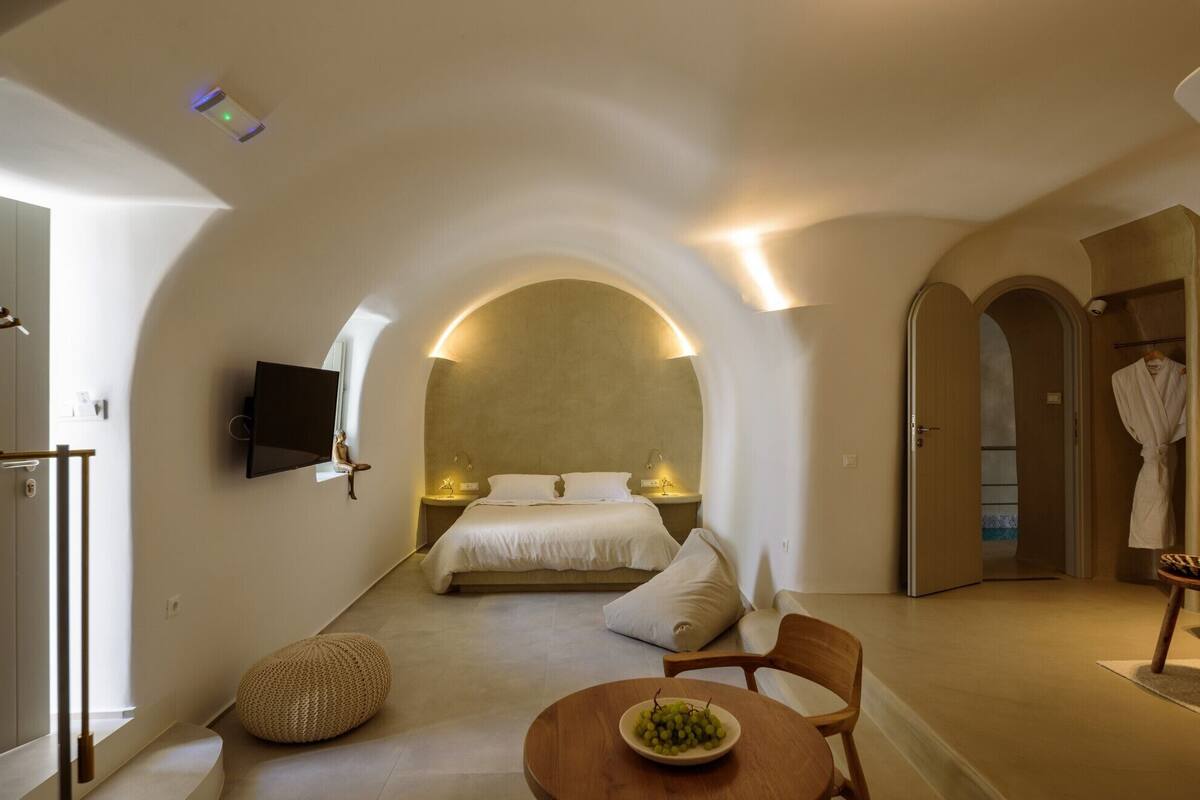 Een moderne hotelkamer met een bed, een televisie, een zithoek met een tafel en stoelen, en een beeld.