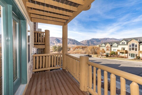 A wooden porch with a view of a row of townhouses and mountains in the background.
