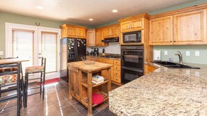 Una cocina con armarios de madera, encimera de granito, refrigerador, microondas y estufa.