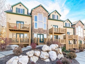 A multi-story residential building with a stone facade, multiple balconies, and a stone pathway leading to the entrance.