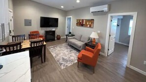 A spacious living room with a flat-screen TV, a sofa, and a dining area with a table and chairs. - Stylish and cozy 2 bed (Brighton)
