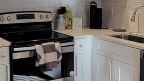 A kitchen with white cabinets, a microwave, a stove, and a sink.