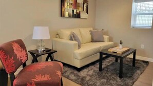 A living room with a sofa, a chair, a coffee table, and a lamp.