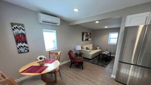 A modern living room with a dining area, a sofa, and a refrigerator.