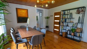 A dining area with a wooden table and chairs, a bookshelf, and a ceiling light fixture. - 4 Bedroom fun house - spa, sauna, fire pits, pool table, 4 TV's, 2 outdoor areas (Healesville)
