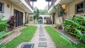 Une cour intérieure avec un chemin central bordé de verdure et un bâtiment doté de balcons.