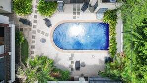 Une piscine sur le toit, entourée de chaises longues et agrémentée d’un petit jardin.