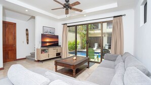 Un salon avec un canapé, une table basse, un téléviseur et un ventilateur de plafond.