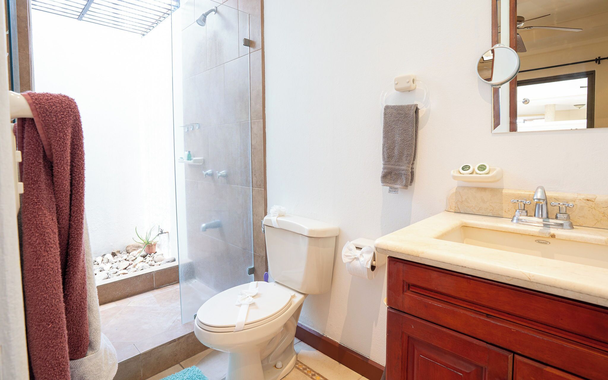 Et badeværelse med bruser, toilet, håndvask og spejl.