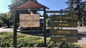 Een bord van Radiant Health met diensten: infrasauna, massage, reflexologie en reiki.