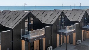 A row of modern beach huts with sloped roofs, wooden accents, and glass balconies overlooking the sea. - Stunning apartment in Slagelse (Slagelse)