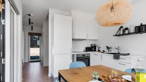 A modern kitchen with white cabinets, a wooden dining table, and a hanging light fixture. - Stunning apartment in Slagelse (Slagelse)