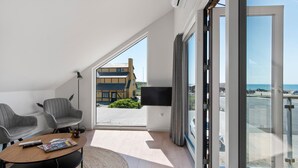 A modern living room with a balcony, a flat-screen TV, and a view of the sea. - Stunning apartment in Slagelse (Slagelse)