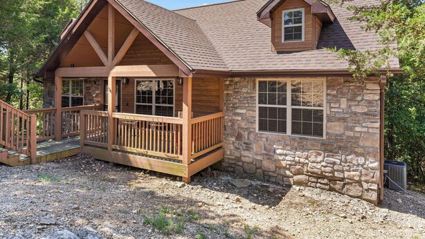 A stone cabin with a wooden deck and a small porch.