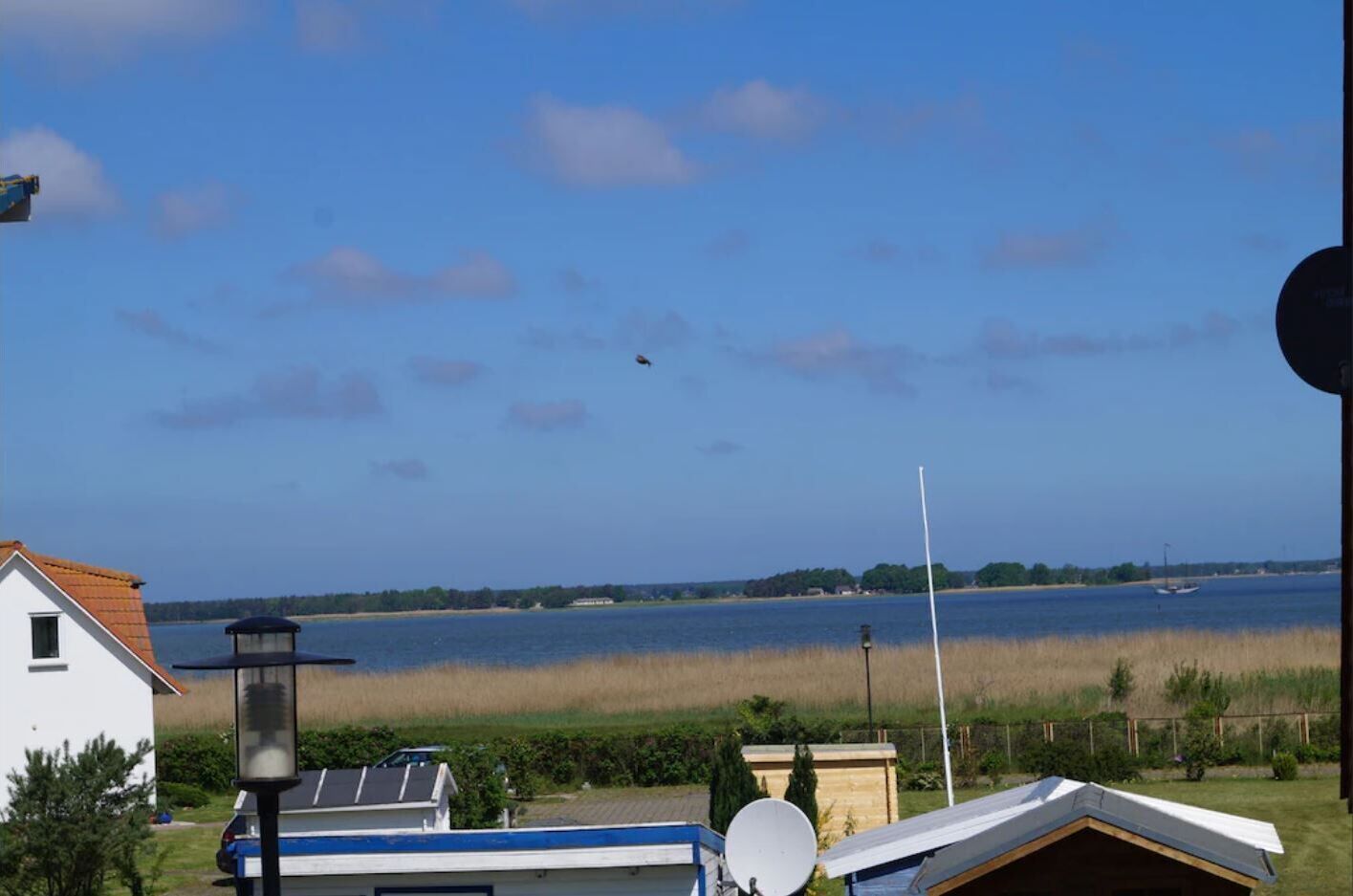 A residential area with a view of a lake, a house, and a satellite dish.