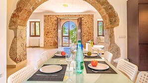 A dining area with a stone archway, a table set for four, and a view through the archway.